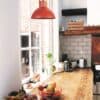 Lámpara de techo roja en cocina rústica con ventana y detalles naturales.