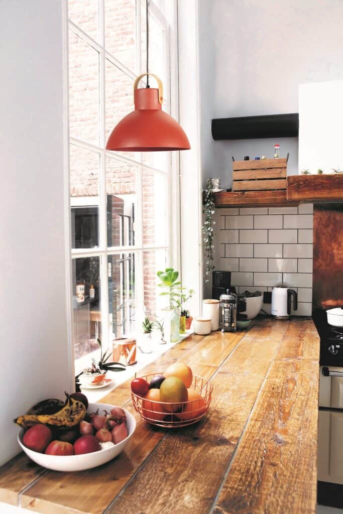 Lámpara de techo roja en cocina rústica con ventana y detalles naturales.