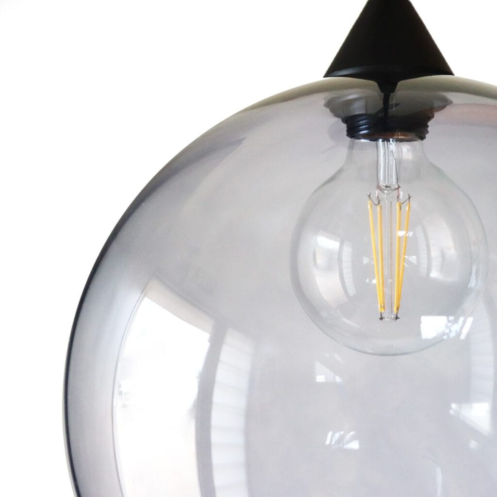 Lámpara colgante moderna con bombilla visible y pantalla de vidrio transparente.